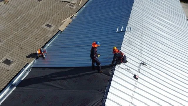 Trabajadores instalando planchas nuevas en la techumbre